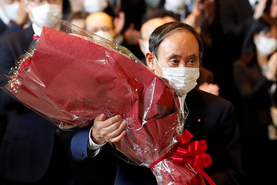 지난 4일 스가 요시히데 일본 총리가 일본 도쿄 지요다구 총리 관저에서 퇴임할 당시 모습. 대형 꽃다발을 안고, 인사를 하고 있다. 로이터 뉴스1