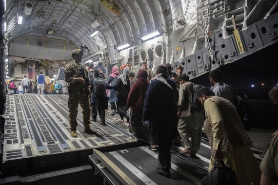[카불=AP/뉴시스] 미 공군이 제공한 사진으로 22일 탈레반 치하의 아프간을 탈출하려는 아프간 현지인과 외국 체류자가 수도 카불의 하마드 카르자이 국제공항에서 미군의 C-17 글로브매스터3 수송기에 오르고 있다. 2021. 8. 24.