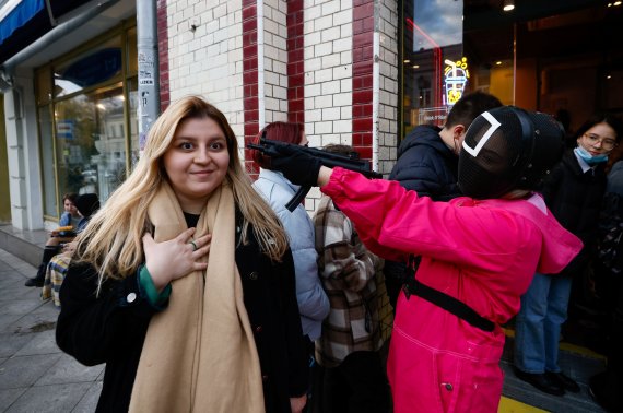 A waiter of Korean cafe Chick O'Rico in a costume of a personage from television series Squid Game aims a toy gun at a visitor in Moscow, Russia October 15, 2021. REUTERS/Maxim Shemetov /REUTERS/뉴스1 /사진=로이터뉴스1