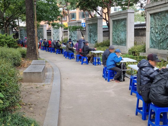 18일 오전 11시반쯤 서울 종로 탑골공원에서 무료 배식을 받은 어르신들이 일렬로 간이식탁에 앉아 식사를 하고 있다. 사진=김해솔 기자