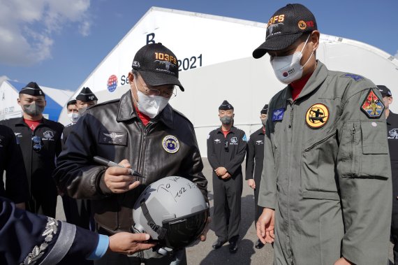문재인 대통령이 20일 경기도 성남시 서울공항에서 열린 2021 서울 국제 항공우주 및 방위산업 전시회(ADEX) 개막 기념행사에 참석해 시범비행을 마친 공군 특수비행팀 블랙이글스 대원들과 인사하며 FA-50 비행시 착용한 헬멧에 사인을 하고 있다. 2021.10.20/뉴스1 © News1 이광호 기자
