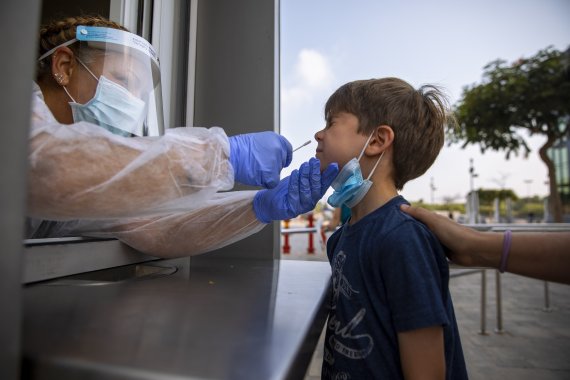 [텔아비브=AP/뉴시스] 지난 8월 9일 텔아비브의 검사소에서 한 보건 노동자가 코로나19 검사를 위해 아이의 샘플을 채취하고 있다. 2021.10.21. /사진=뉴시스