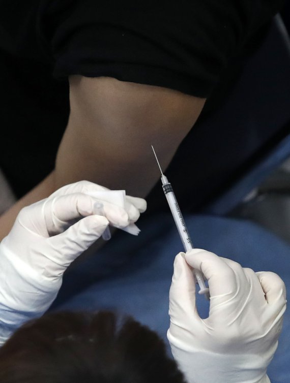 한 의료진이 코로나19 백신을 접종하기 위해 접종자의 팔에 주사바늘을 꼽고 있다.<div id='ad_body3' class='mbad_bottom' ></div> /사진=뉴시스