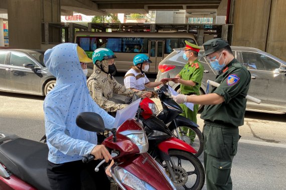 코로나19 확산으로 봉쇄 조치를 연장한 베트남 하노이의 한 검문소에서 경찰이 출근 주민들의 여행 허가서를 조사하고 있다. © 로이터=뉴스1 © News1 우동명 기자