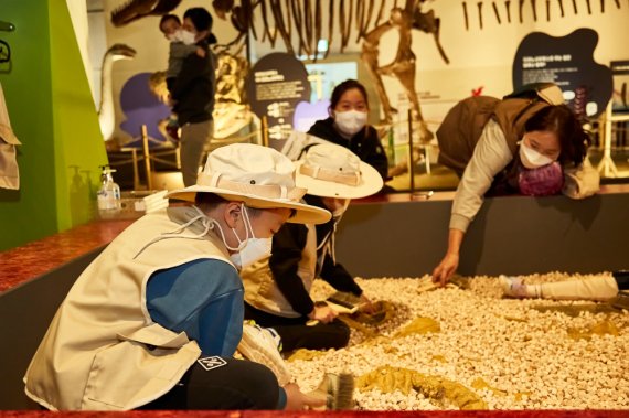 국립부산과학관 김진재홀에서 진행하는 '다이노소어' 특별기획전에 마련된 체험존에서 어린이들이 편백나무 알갱이 속에 숨어있는 공룡뼈를 찾아보고 있다. 부산과학관 제공