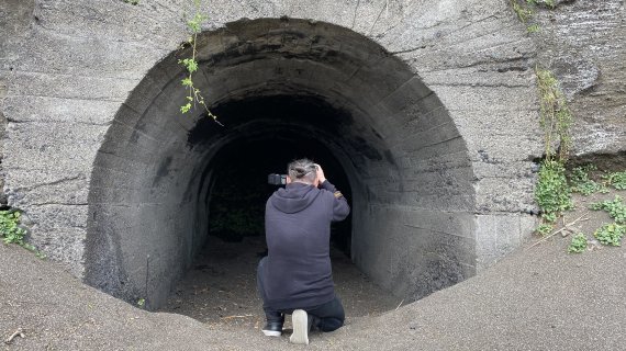 제주도 성산일출봉 아래 해변에 일본군이 태평양전쟁 말기에 만든 해군기지. 사진을 찍고 있는 뒷모습은 일본인 사진작가다. 오랫동안 한국에서 위안부 할머니들을 돌보며 생활했다. 그 또한 ‘동아시아 워크숍’ 맴버다. (김명준 감독 제공)© 뉴스1