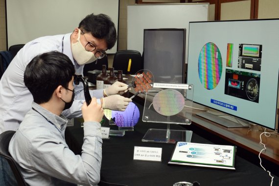 한국전자통신연구원(ETRI) 조남성 박사(뒤)가 저온공정이 가능한 포토레지스트 소재로 OLED 디스플레이용 기판을 만들어 설명하고 있다. ETRI 제공