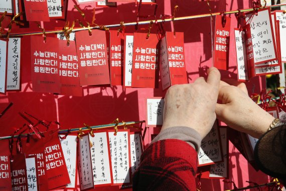 서울 종로구 조계사에서 한 시민이 수험생 응원 문구를 적은 소원지를 매달고 있다. 2021.11.15/뉴스1 © News1 임세영 기자