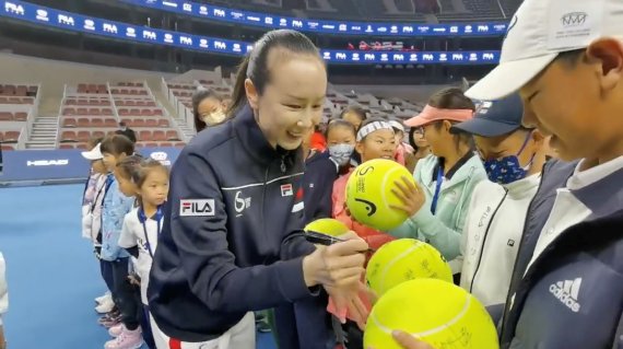 중국 테니스 선수 펑솨이가 21일 중국 베이징 청소년 테니스 대회 결승전 개막식에 참석해 대형 테니스공에 사인하고 있다.로이터뉴스1