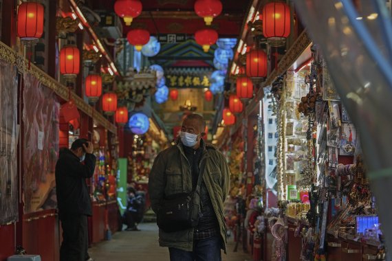 2021년 11월17일(현지시간) 중국 베이징의 인기 관광지인 첸먼 거리 인근 기념품 상가에서 마스크를 쓴 행인이 기념품을 구경하며 지나고 있다. /사진=AP·뉴시스