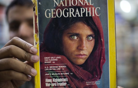【이슬라마바드=AP/뉴시스】파키스탄 검찰은 2일 불법체류 및 공문서 위조혐의로 체포했던 '아프간 소녀' 샤르바트 굴라를 석방했다고 밝혔다. 사진은 지난 달 26일 이슬라마바드의 한 책방에서 한 남성이 굴라가 십대시절 찍어 화제가 됐던 내셔널 지오그래픽 표지를 들어보이고 있는 모습. 2016.11.02