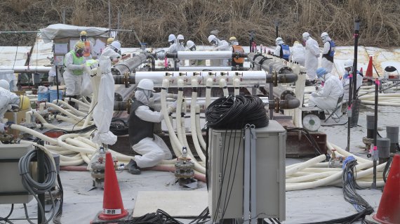 【도쿄=AP/뉴시스】동일본 대지진이 발생한지 오는 11일로 5년이 된다. 사진은 지난 2014년 3월 10일 후쿠시마(福島)현 오쿠마(大熊) 지역에 위치한 후쿠시마 제1원전에서 작업원들이 보호복을 입고 '동토차수벽'을 설치하고 있는 모습. 동토차수벽이란 방사성 물질에 오염된 지하수가 바다로 유입되는 것을 방지하기 위한 장치로, 원전 주변에 길이 약 1.4㎞의 동결관을 설치한 뒤 냉각제를 순환시켜 땅을 얼려, 지하수의 원전 유입을 차단하는 시설이다. 2016.03.08.