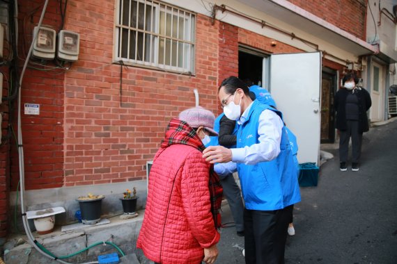 우리카드 김정기 대표이사(오른쪽)가 지난 11월29일 서울 창신 2동에서 진행된 김장김치 전달 행사에서 주민에게 목도리를 걸어주고 있다. 우리카드 제공