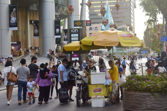 싱가포르 시민들이 지난달 28일(현지시간) 시내 쇼핑가에서 마스크를 쓴 채 쇼핑을 즐기고 있다. 싱가포르는 8일 백신을 맞지 않았을 경우 코로나19에 감염되면 본인이 치료비를 부담토록 했다. AP뉴시스