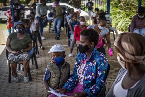 남아프리카공화국 요하네스버그의 코로나19 백신 접종소에 백신을 맞으려는 시민들이 의자에 앉아 기다리고 있다. 오미크론변이가 빠르게 퍼지는 가운데 남아공 하루 신규확진자 수는 이날 전일비 2배 가까이 폭증했다. AP뉴시스