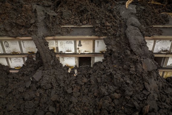 [라팔마=AP/뉴시스] 6일(현지시간) 스페인 카나리아제도 라팔마섬의 쿰브레 비에하 화산에서 용암이 흘러나오면서 라스 만차스 마을의 한 묘지가 화산재로 덮인 채 훼손돼 있다. 2021.12.08.