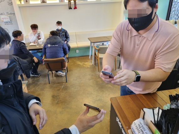 [청주=뉴시스] 안성수 기자 = 9일 충북 청주의 한 카페에서 손님이 업주에게 백신 접종 증명서를 보이고 있다. 정부의 코로나19 특별방역대책 시행으로 식당, 카페 등 접종증명·음성확인제(방역패스) 의무적용시설은 입장객들을 대상으로 백신 접종 증명서나 음성확인서를 확인해야 한다. 2021.12.09. hugahn@newsis.com