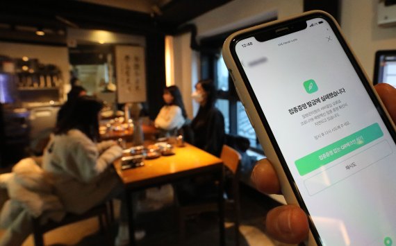 방역패스(접종증명·음성확인제)의 계도기간이 끝나고 의무화가 시작된 13일 서울시내의 한 식당에서 손님이 접종증명 발급 오류 화면을 보이고 있다. 이날 백신 접종을 증명하는 시스템에 일부 오류가 발생해 백신 QR 코드 인증 화면에는 '질병관리청의 서버응답 오류로 코로나19 예방백신 접종 증명 확인이 지연되고 있습니다'고 표시됐다. 2021.12.13/뉴스1 © News1 임세영 기자