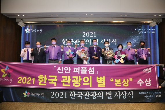 박우량 신안군수와 '퍼플섬' 관계자들이 '2021 한국 관광의 별' 본상 수상을 기념해 사진촬영을 하고 있다.사진=신안군 제공