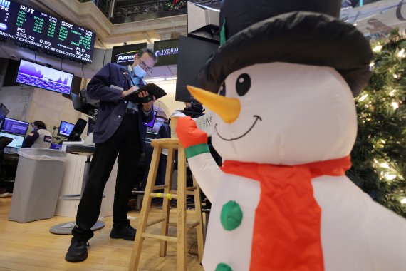 미국 뉴욕 맨해튼의 뉴욕증권거래소(NYSE)에서 지난해 12월 23일(현지시간) 눈사람 장식과 크리스마스 트리가 세워진 가운데 한 트레이더가 태브릿 컴퓨터를 들여다보고 있다. 뉴욕증시의 S&P500 지수는 2021년을 상승률 27%로 마감했다. 로이터뉴스1