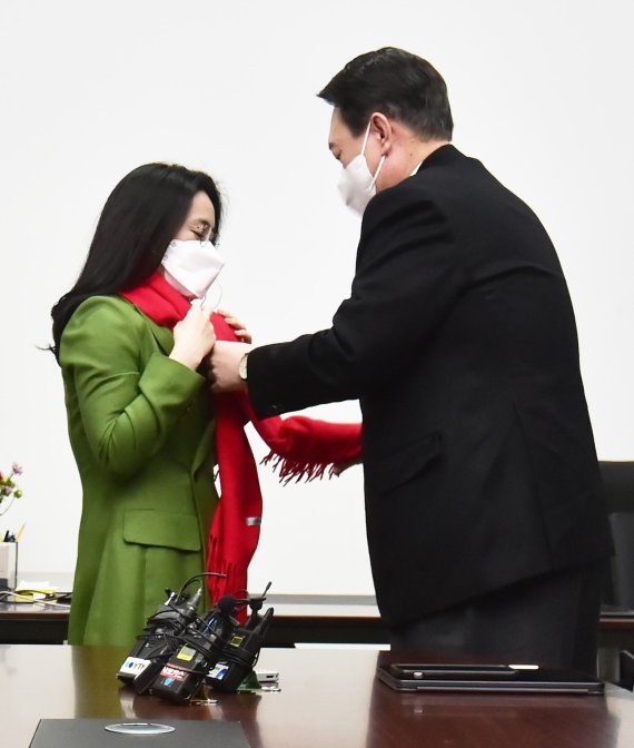 윤석열 국민의힘 대선 후보가 20일 서울 여의도 새시대준비위원회 위원장실에서 열린 영입인사 환영식에서 신지예 한국여성정치 네트워크 대표에게 환영 목도리를 걸어주고 있다. 신 대표는 윤 후보 직속 기구인 새시대준비위원회 수석부위원장으로 활동한다. 2021.12.20/뉴스1 © News1 구윤성 기자