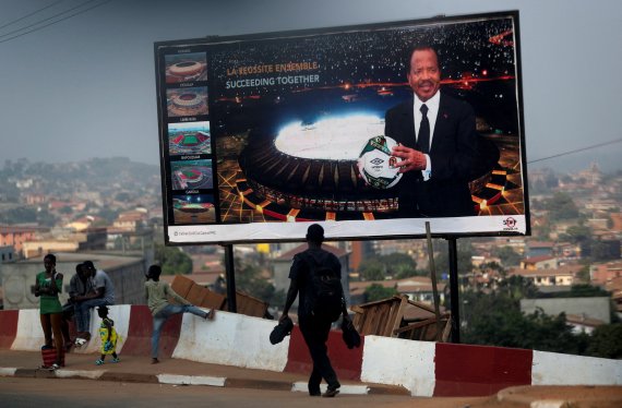 서아프리카 카메룬의 수도 야운데에서 지난 8일 시민들이 아프리카 네이션스컵을 홍보하는 광고판 앞을 지나고 있다.로이터뉴스1