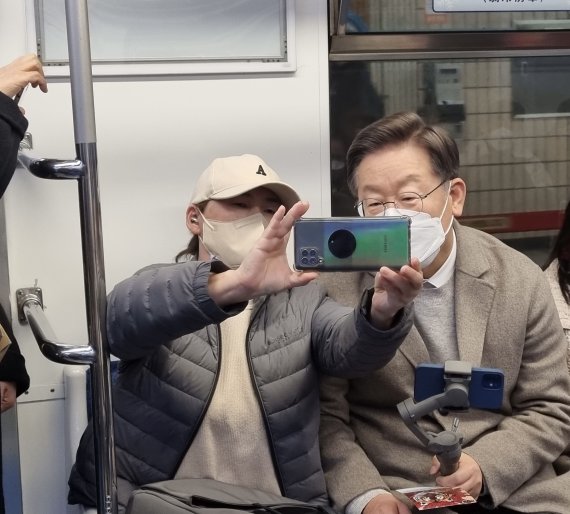 이재명 더불어민주당 대선 후보가 7일 서울 숙대입구역에서 지하철을 이용해 이동하며 '걸어서 민심 속으로' 유튜브 라이브 방송을 하던 중 시민과 사진을 찍고 있다. 사진=이재명 후보 캠프 제공, 뉴시스.