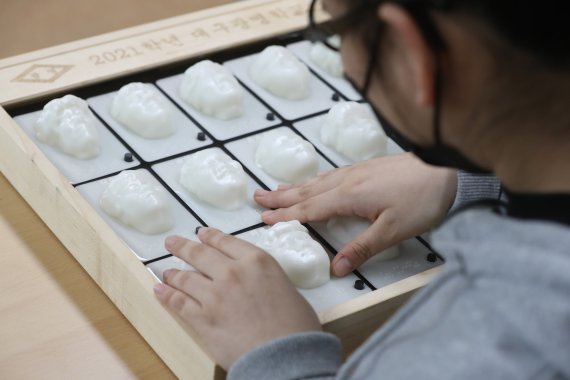 지난 11일 대구 남구 대명동 시각장애인 교육기관 대구광명학교에서 열린 2021학년 졸업식에서 초등학교 과정 졸업생이 3D프린터로 제작된 졸업앨범에 손을 올려 친구와 선생님 얼굴을 만져보고 있다. 2022.1.11/뉴스1 © News1 공정식 기자