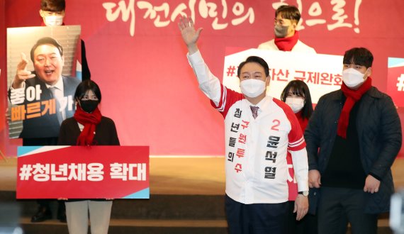 윤석열 국민의힘 대선 후보가 1월 21일 오후 대전 서구 오페라웨딩홀에서 열린 대전 선거대책위원회 필승결의대회에서 '청년들의 구원투수' 문구가 적힌 유니폼을 입은 뒤 손인사를 하고 있다. ©뉴스1, 2022년 1월