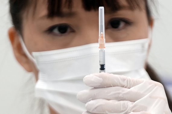 22일 일본 도쿄 스미다구 소재 스카이트리 단지 내 코로나19 백신 예방접종센터에서 한 의료진이 주사기에 모더나 백신을 투입한 후 투여량을 확인하고 있다. AP뉴시스