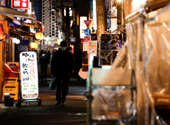 25일 일본 도쿄에서 마스크를 쓴 시민이 술집 골목을 지나고 있다.로이터뉴스1