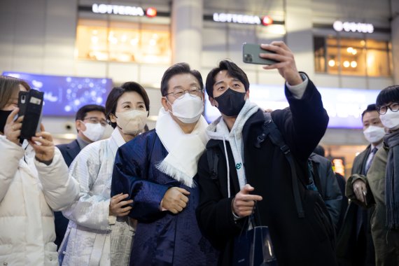 이재명 더불어민주당 대선 후보가 설 연휴인 31일 부인 김혜경 씨와 함께 서울 용산역을 방문해 귀성객들과 기념사진을 찍고 있다.민주당 선대위 제공
