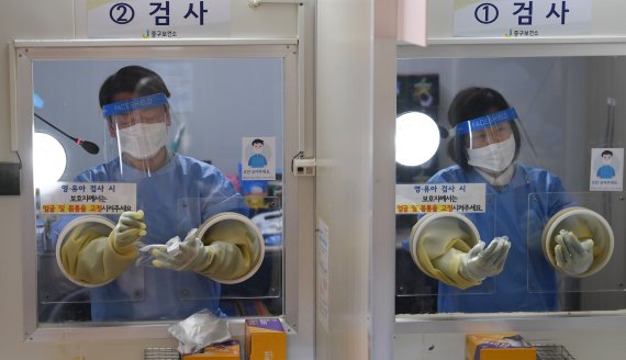 안철수 국민의당 대선 후보가 설 연휴 마지막 날인 2일 서울 중구보건소 선별진료소에서 부인 김미경 교수와 함께 코로나19 검체 채취 의료봉사 활동을 하고 있다. 이날 동행한 딸 안설희 박사는 행정 업무 등을 지원했다. 2022.2.2/뉴스1 © News1 오대일 기자