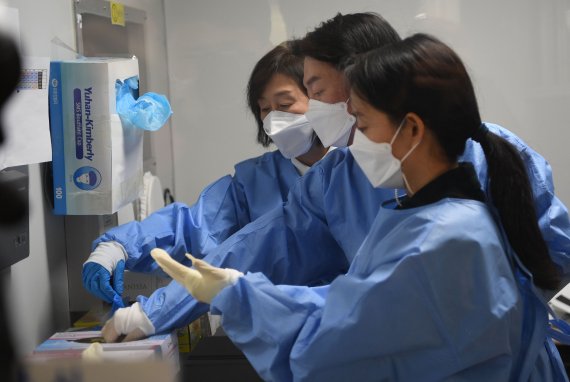 안철수 국민의당 대선 후보가 설 연휴 마지막 날인 2일 서울 중구보건소 선별진료소에서 부인 김미경 교수, 딸 안설희 박사와 함께 코로나19 의료 봉사를 위해 가운과 장갑을 착용하고 있다. 이날 안 후보 부부는 검체 체취를, 딸 안설희 박사는 행정 업무 등을 지원했다. 2022.2.2/뉴스1 © News1 오대일 기자