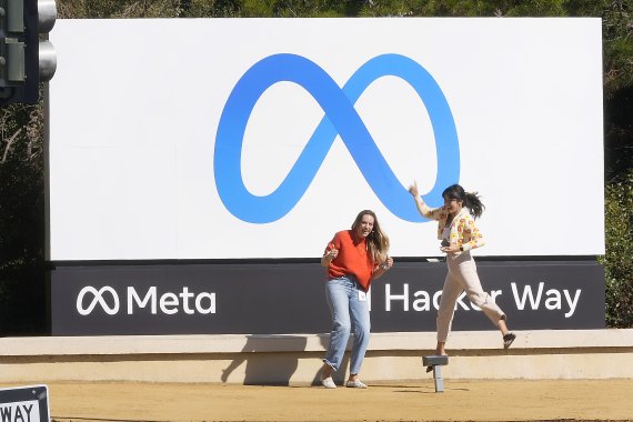 미국 캘리포니아주 멘로파크의 메타플랫폼스 본사에 내걸린 회사 대형 로고 앞에서 지난해 10월 28일(현지시간) 직원들이 사명 개정을 반기며 포즈를 취하고 있다. AP뉴시스