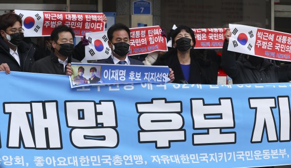 [서울=뉴시스] 최진석 기자 = 박근혜 서포터즈 중앙회 등 보수진영 애국 단체 일부 회원들이 4일 서울 여의도 더불어민주당 중앙당사 앞에서 이재명 더불어민주당 대선 후보 지지 펼침막을 들고 있다. 2022.02.04. myjs@newsis.com