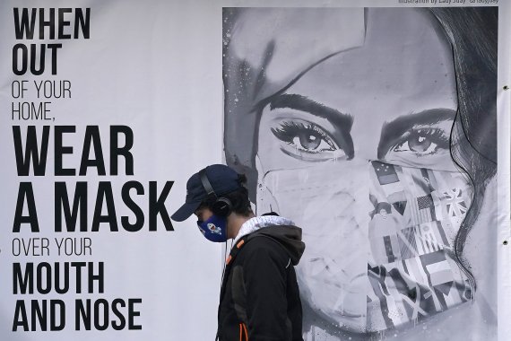 미국 샌프란시스코의 한 시민이 마스크 착용을 권호하는 광고 앞을 마스크를 착용한 채 걸어가고 있다. /사진=AP뉴시스