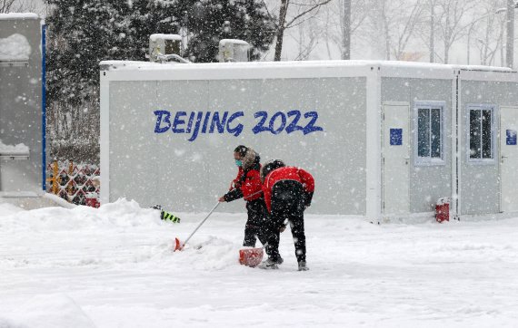 13일 2022 베이징 동계올림픽이 진행중인 내셔널 아쿠아틱 센터에서 자원봉사자 및 관계자들이 눈을 치우고 있다. 뉴시스 제공