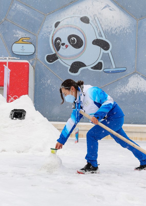 2022 베이징 동계올림픽 개막 후 첫 눈이 내리는 13일 컬링 경기장인 중국 베이징 국립아쿠아틱센터에서 자원봉사자가 눈과 제설도구를 이용해 컬링 포즈를 따라하고 있다. 2022.2.13/뉴스1 © News1 안은나 기자