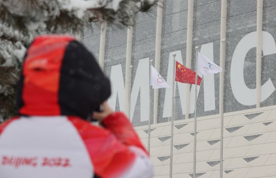 2022 베이징 동계올림픽 개막 후 첫 눈이 내리는 13일 중국 베이징 메인미디어센터 앞에서 한 관계자가 눈 내리는 풍경을 스마트폰에 담고 있다. 2022.2.13/뉴스1 © News1 안은나 기자