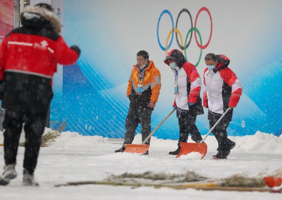 2022 베이징 동계올림픽 개막 후 첫 눈이 내리는 13일 중국 베이징 국립아쿠아틱센터에서 관계자들이 제설작업을 하고 있다. 2022.2.13/뉴스1 © News1 안은나 기자