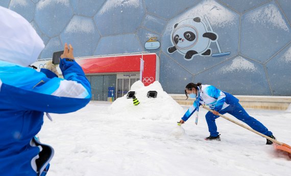 2022 베이징 동계올림픽 개막 후 첫 눈이 내리는 13일 컬링 경기장인 중국 베이징 국립아쿠아틱센터에서 자원봉사자가 눈과 제설도구를 이용해 컬링 포즈를 따라하고 있다. 2022.2.13/뉴스1 © News1 안은나 기자
