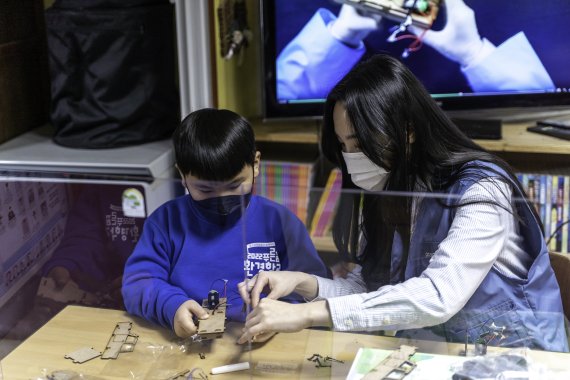 포스코케미칼 직원이 포항 지역아동센터에서 진행된 ‘푸른꿈 환경학교’에서 어린이와 함께 전기차 모형을 조립하는 모습. 포스코케미칼 제공