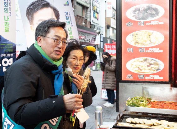 김동연 새로운물결 대선 후보(왼쪽)가 16일 서울 명동 한 분식점에서 어묵을 먹으며 상인과 대화하고 있다. 뉴시스