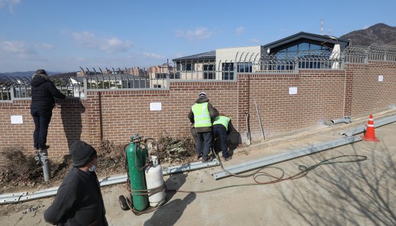16일 오전 대구 달성군 유가읍 쌍계리 박근혜 전 대통령 사저로 알려진 주택 담장 주변 가드레일 해체작업이 진행되고 있다. 옆에서 한 방문객이 가드레일 기둥에 올라가 휴대전화 카메라로 사저를 찍고 있다. 주택이 지어질 당시 담장 보호를 위해 설치됐던 가드레일이지만, 박 전 대통령 사저라는 소식이 전해진 뒤 많은 방문객들이 가드레일을 밟고 올라가 주택을 들여다보는 등 사생활 침해 논란이 일자 달성군은 업체를 선정해 이날 오전부터 해체에 들어갔다. 2022.2.16/뉴스1 © News1 공정식 기자