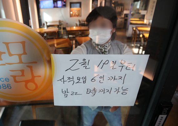 18일 서울 광화문의 한 음식점에서 관계자가 새 거리두기 조정안 문구가 적힌 안내문을 부착하고 있다. 2022.2.18/뉴스1 © News1 김진환 기자