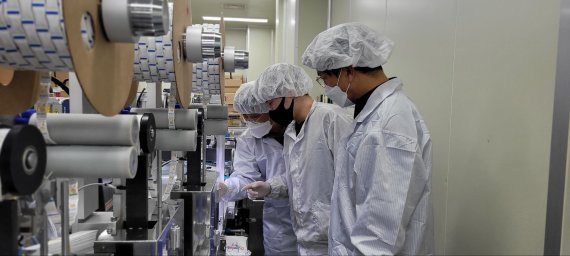 충남 천안에 위치한 자가진단키트 생산업체 '젠바디'에서 24일 삼성전자 스마트공장 전문가와 젠바디 직원(가운데)이 자가진단키트 조립 라인을 점검하고 있다.