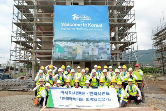 한국해비타트 희망의 집짓기 봉사활동에 참여한 아시아시멘트와 한라시멘트 직원들이 기념촬영을 하고 있다.