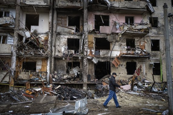 25일(현지시간) 우크라이나 키예프에서 주민들이 러시아의 로켓 공격으로 파손된 건물 앞을 지나고 있다. 2022.02.25. /사진=뉴시스