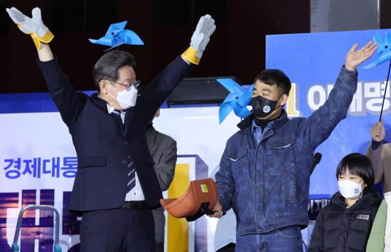 [울산=뉴시스] 최동준 기자 = 이재명 더불어민주당 대선 후보가 27일 울산 남구 롯데백화점 앞에서 열린 유세에서 용접공 장갑을 선물 받고 손을 들어올리고 있다. 2022.02.27. photocdj@newsis.com